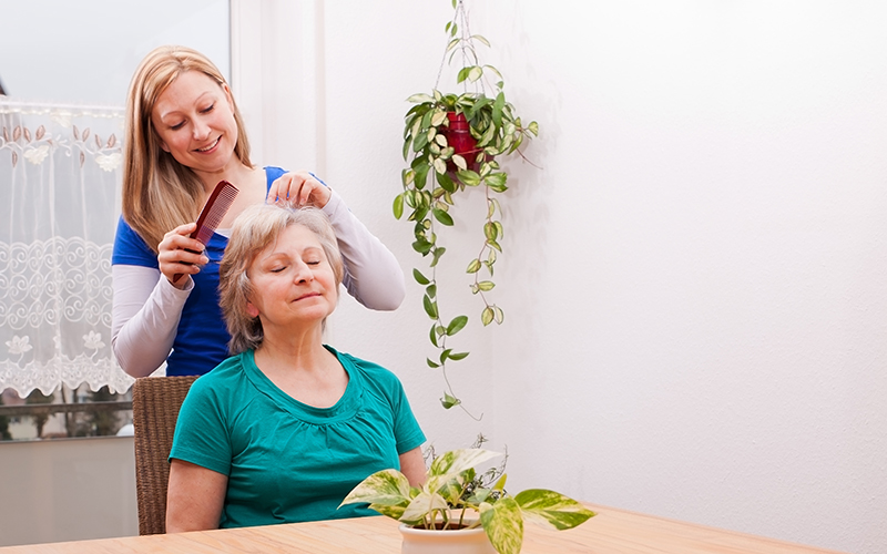 blonde young woman combing seniors hair